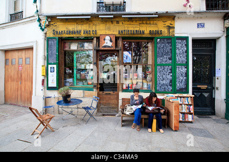 Due donne che leggono fuori dalla libreria Shakespeare and Company nel quartiere Latino di Parigi, Francia Foto Stock