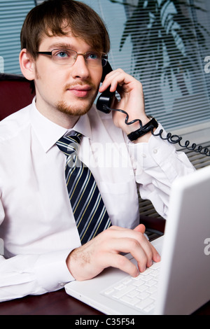 Ritratto di imprenditore bello parlare con il suo partner al telefono in ufficio Foto Stock