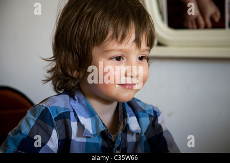 2 anno vecchio ragazzo seduto nella sedia alta a tavola guardando cartoni animati Foto Stock