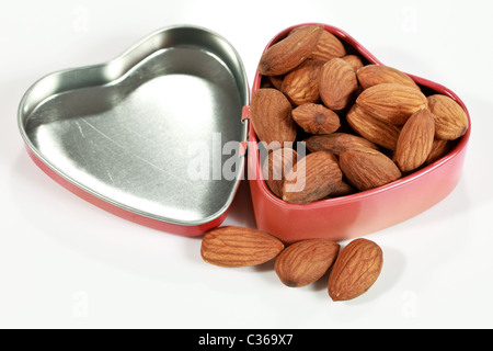 Materie le mandorle in un cuore a forma di scatola di stagno indicazione mandorle sono buon cuore cibo Foto Stock