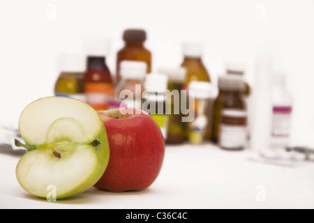 Il verde e le mele rosse di fronte a molte pillole e flaconi portapillole Foto Stock