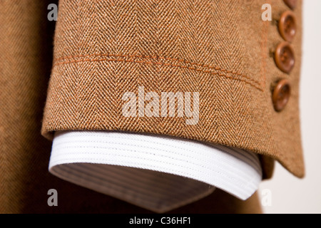 Primo piano della tuta, dettaglio del bracciale marrone e camicia bianca Foto Stock