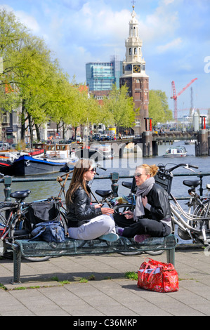 Amsterdam, Paesi Bassi. Vista da Sint Antoniesluis di Oude Schans canal e Montelbaanstoren (torre). Due ragazze parlano Foto Stock