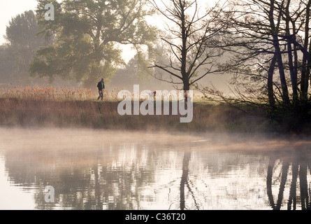 Uomo che cammina il cane in campagna all alba di una mattina di primavera, il Tamigi a Wallingford, Oxfordshire, Regno Unito Foto Stock