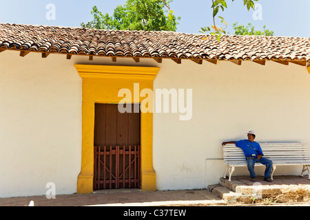 Un uomo su una panchina in ombra di un piastrellate con tetto di casa in Copala Sinaloa membro Messico Foto Stock