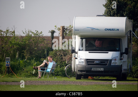 Uomo seduto la lettura al di fuori di casa a motore Foto Stock