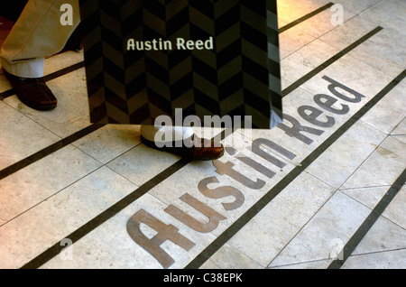 Un uomo lasciando una Austin Reed negozio con i suoi acquisti. Foto Stock