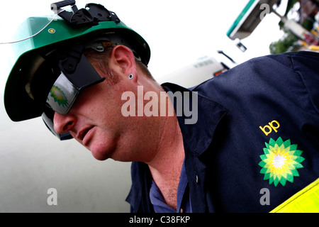 Un dipendente di BP in indumenti protettivi (PPE) riempimento le pompe in corrispondenza di una stazione di benzina Foto Stock