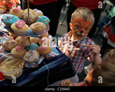 Ragazzo con Facepainted come leone alla torte fatte in casa stallo a Royal Wedding Street Party Foto Stock