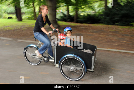 Una donna alla guida i suoi figli con un cargo bike Foto Stock