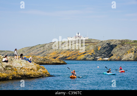 Llaneilian, Isola di Anglesey, Galles del Nord, Regno Unito. Porth Eilian con persone canoa e Point Lynas faro al di là Foto Stock