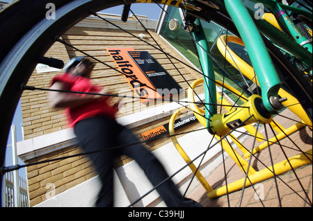 Un ciclista a piedi per la sua moto al di fuori di un Halfords store. Foto Stock