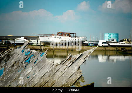 Un colorato rovinato barca su una vecchia corda e il nodo sulla prua di una barca nel fiume Arun con un cantiere in background. Poco Foto Stock