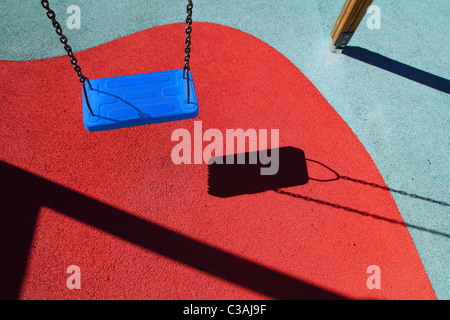 Parco Blu swing o pavimento rosso il parco giochi per i bambini con le ombre Foto Stock