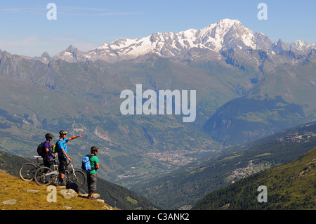 Tre i ciclisti di montagna guarda attraverso la valle dal La Plagne ski resort e al Mont Blanc e la città di Bourg-Saint-Maurice Foto Stock