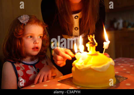 Un bambino di 5 anni la ragazza con i capelli di zenzero festeggia il suo compleanno con una torta di compleanno Foto Stock