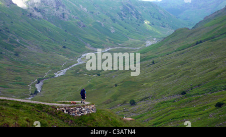 Un modo di Cumbria walker in direzione nord sul picchetto passare verso Langstrath Beck. Foto Stock