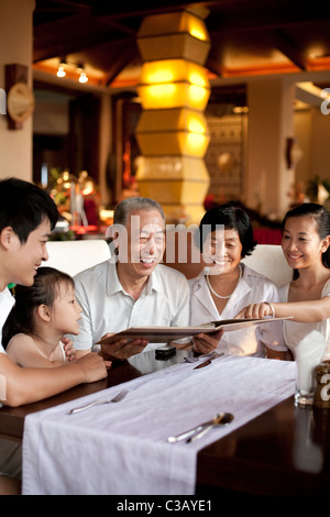 La famiglia felice guardando attraverso un menu Foto Stock