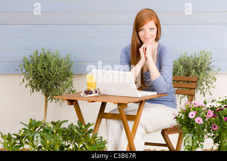 Terrazza estiva redhead donna con notebook in giardino Foto Stock