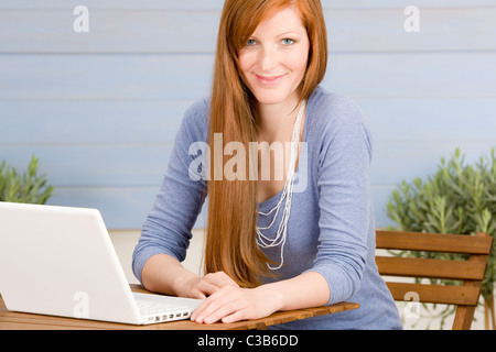 Terrazza estiva redhead donna con notebook in giardino Foto Stock