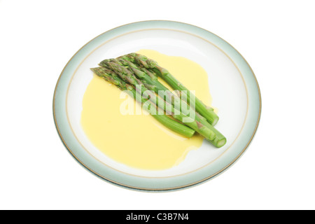I germogli di asparagi in salsa olandese su una piastra isolata contro bianco Foto Stock