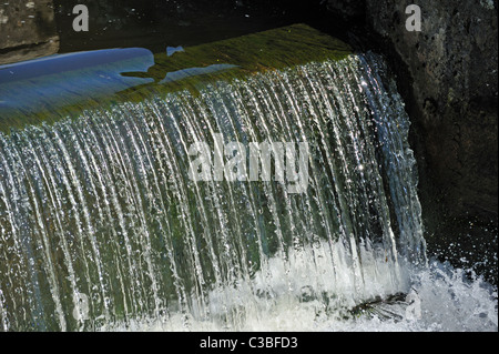 L'acqua che scorre sulle serrature abbandonati sulla Northern raggiungere il Lancaster a Kendal canal. Tewitfield, Cumbria, England, Regno Unito Foto Stock