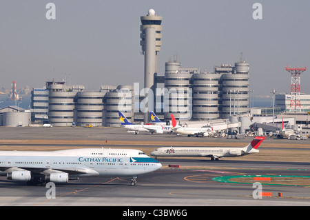 Aeromobile / aerei su asfalto con torre in background a 'Haneda di Tokyo International Airport (Giappone) Foto Stock