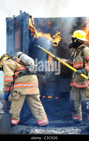 Stati Uniti d'America di emergenza in caso di incendio i vigili del fuoco in lotta blaze nel contenitore di spedizione Foto Stock