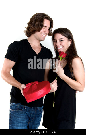 L'uomo tiene a forma di cuore scatola di cioccolatini e la donna può contenere una singola rosa rossa. Entrambi sono molto felice. Perfetto per il giorno di San Valentino. Foto Stock
