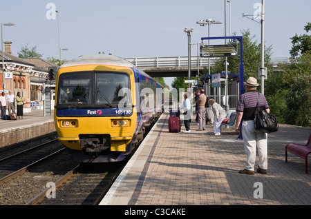 Primo grande Western treno di Gatwick si avvicina la stazione ferroviaria con i passeggeri in attesa sulla piattaforma. Nord Camp, Inghilterra, Regno Unito, Gran Bretagna Foto Stock