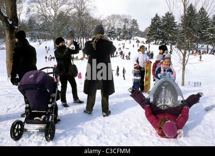 New York City gruppi di persone nel Central Park che si divertano con le attività invernali. Famiglie con bambini che giocano sulla neve a Cedar Hill. Lato superiore est. Foto Stock