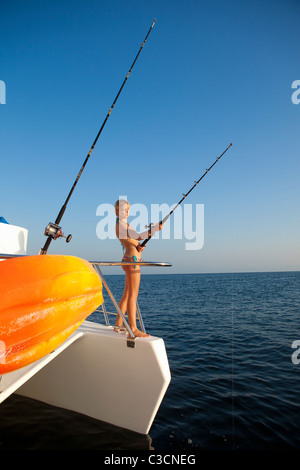 Giovane donna con la canna da pesca su yacht Foto Stock