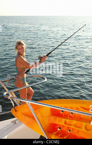 Giovane donna con la canna da pesca su yacht Foto Stock