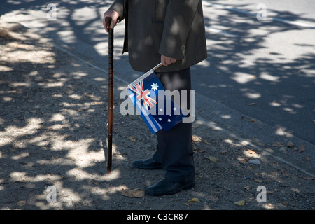 Uomo con la canna da zucchero tenendo la bandiera australiana nel corso di Anzac Day in Adelaide Australia Foto Stock