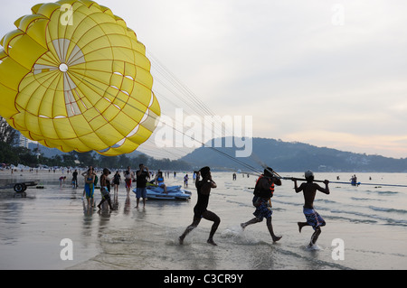 L uomo non identificato (in centro) parasail al tramonto su FEB 6,2011 a Patong Beach, Phuket, Tailandia Foto Stock