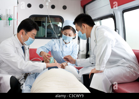 I medici hanno il trattamento di un paziente in un ambulanza Foto Stock