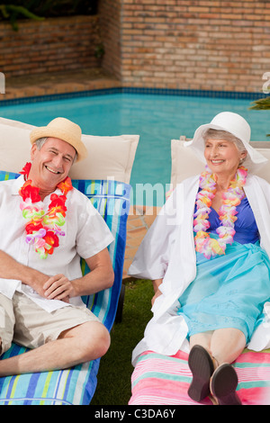 Coppia senior Sdraiati accanto alla piscina Foto Stock