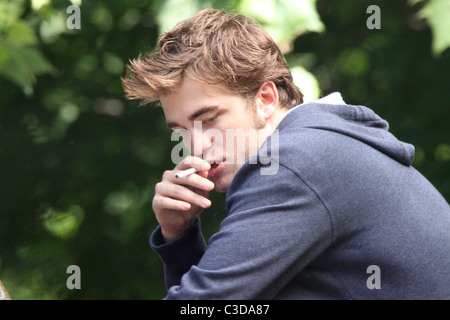 Robert Pattinson fuma una sigaretta sul set del suo nuovo film "Ricordami" durante la ripresa sulla posizione in un parco nel cuore di Manhattan. Foto Stock