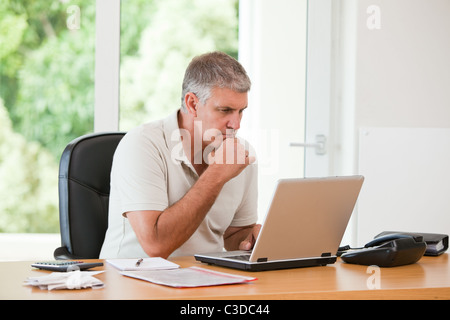Uomo al lavoro sul suo computer portatile Foto Stock