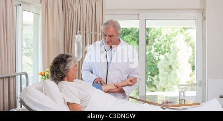 Senior medico tenendo la pressione del sangue del paziente Foto Stock