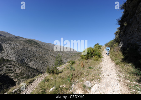 La donna gli escursionisti a piedi verso il basso mozarab trail, vicino a Benimaurell, Vall de Laguart, provincia di Alicante, Valencia, Spagna Foto Stock