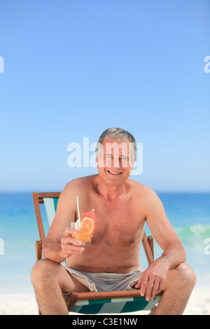 Senior uomo bevendo un cocktail sulla spiaggia Foto Stock