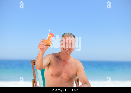 Senior uomo bevendo un cocktail sulla spiaggia Foto Stock