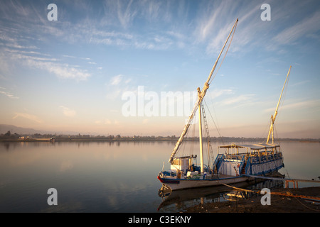Un dahabiya ormeggiato sulle rive del fiume Nilo in acqua calma al tramonto, Egitto Foto Stock