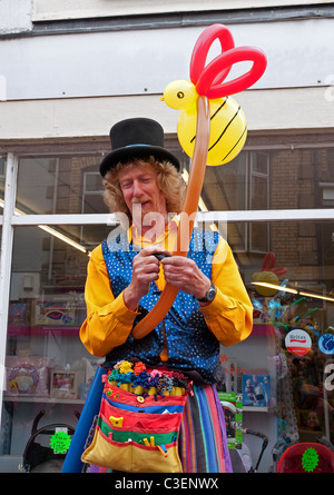 Un artista di strada rendendo i modelli di palloncino in Camborne, Cornwall, Regno Unito Foto Stock