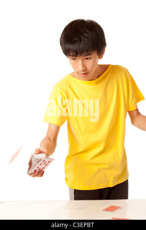 Cinese teenage Asian boy giocare con carte contro uno sfondo bianco Foto Stock