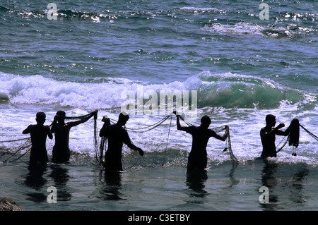 Silhouette pescatori posa reti Ambalama spiaggia vicino Galle costa meridionale dello Sri Lanka Foto Stock