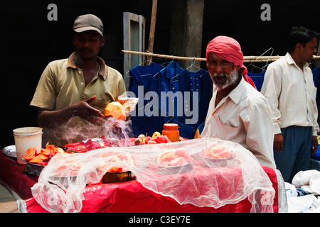 Fornitore per la vendita di frutta chaat presso un mercato in stallo, New Delhi, India Foto Stock