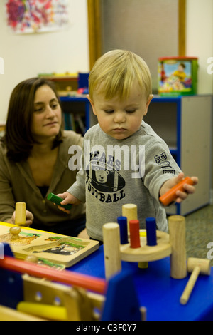 Scuola materna bambino sviluppa mano coordinazione occhio attraverso la riproduzione con tipo puzzle giocattoli. Foto Stock