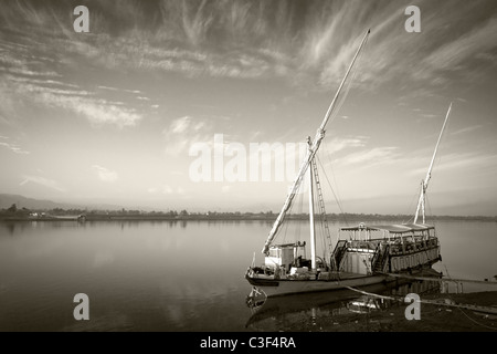 Un nero di seppia colpo di dahabiya ormeggiato sulle rive del fiume Nilo in acque calme, Egitto Foto Stock